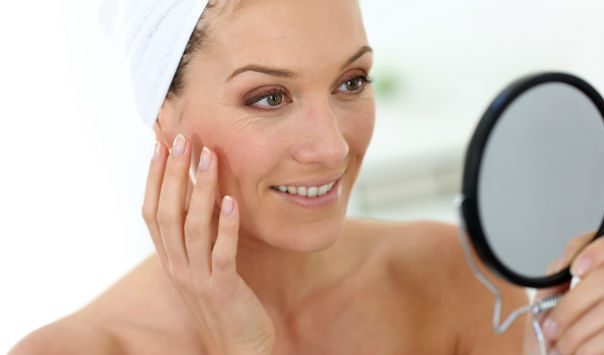 woman with a towel on her hair looking in a mirror
